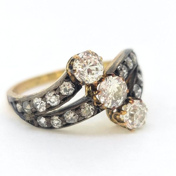 Victorian Antique Diamond Three Stone Banded Ring, diamond trilogy vertically set in asymmetrical design flanked by diamond banded shoulders in silver upon 18ct yellow gold