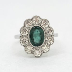 Modern Emerald and Diamond Floral Cluster Ring in Platinum, central 1.30ct oval emerald surrounded by 1.35cts sparkling diamonds rubover set in platinum