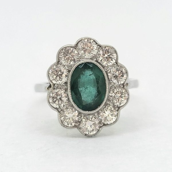 Modern Emerald and Diamond Floral Cluster Ring in Platinum, central 1.30ct oval emerald surrounded by 1.35cts sparkling diamonds rubover set in platinum