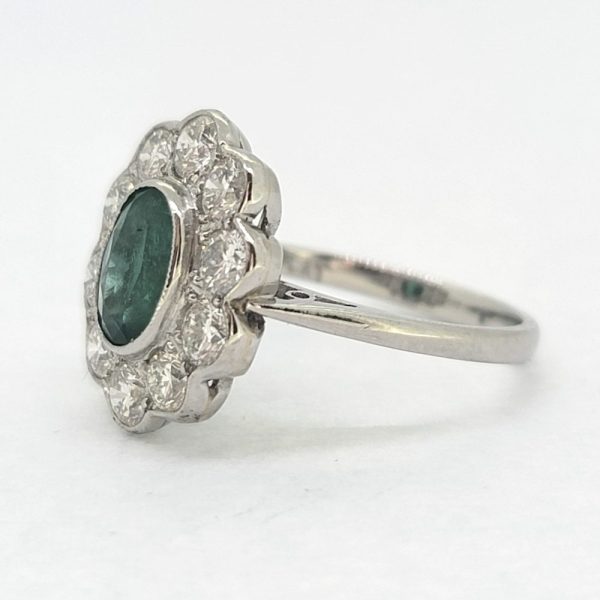 Modern Emerald and Diamond Floral Cluster Ring in Platinum, central 1.30ct oval emerald surrounded by 1.35cts sparkling diamonds rubover set in platinum