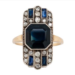 Art Deco Sapphire and Diamond Tablet Ring, 4.50 octagonal step-cut sapphire flanked top and bottom by rows of sparkling diamonds with sapphire accents in platinum to 18ct gold. Circa 1930s