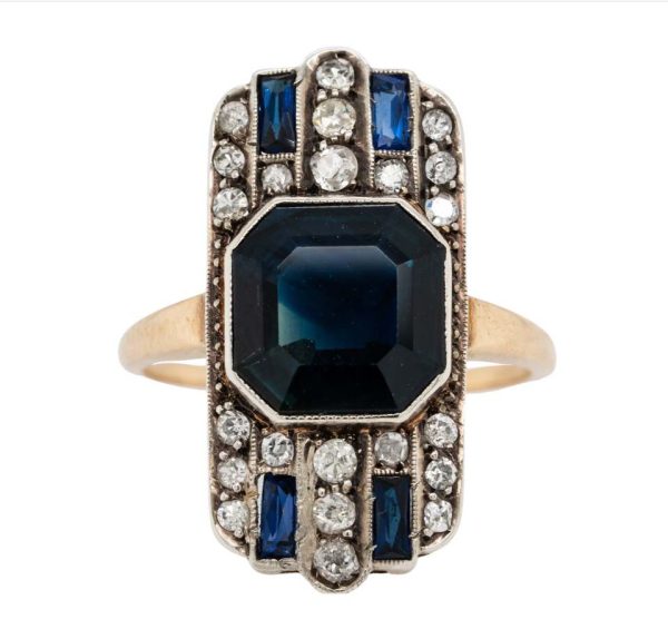 Art Deco Sapphire and Diamond Tablet Ring, 4.50 octagonal step-cut sapphire flanked top and bottom by rows of sparkling diamonds with sapphire accents in platinum to 18ct gold. Circa 1930s