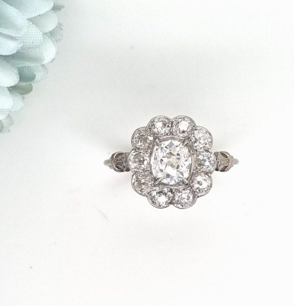 Vintage old cut diamond cluster ring with cushion shape old mine cut 0.90 carat diamond in the centre surrounded by 10 diamonds totaling 1.15 carats set in platinum.