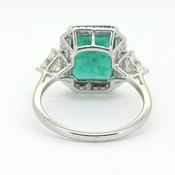 3.85ct Emerald and Diamond Cluster Ring with Trillion Diamond Sides, 3.85ct emerald-cut emerald within brilliant-cut diamond border with trillion-cut diamond to each side in 18ct white gold