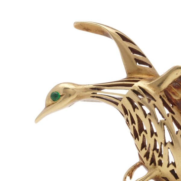 Bird brooch in gold with emerald eye.