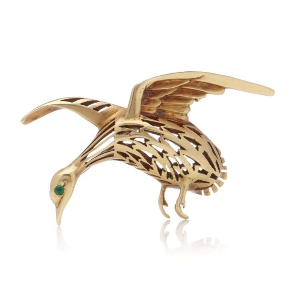 Bird brooch in gold with emerald eye.