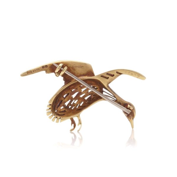 Bird brooch in gold with emerald eye.