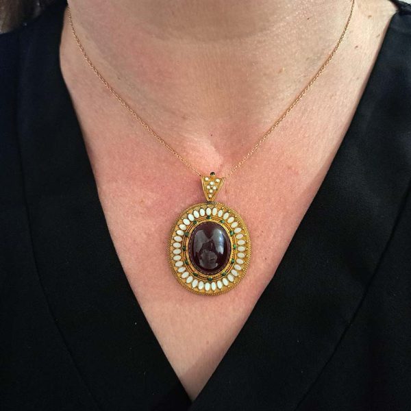 Antique Archaeological Revival Garnet Enamel and Gold Pendant, yellow gold pendant with large oval cabochon-cut garnet accented with white enamel and green enamel decorated surround