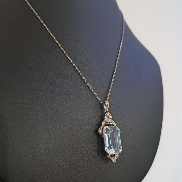 Art Deco Aquamarine and Diamond Pendant, 10.47ct emerald-shaped step-cut aquamarine accented with diamond-set geometric top and bottom in 14ct white gold