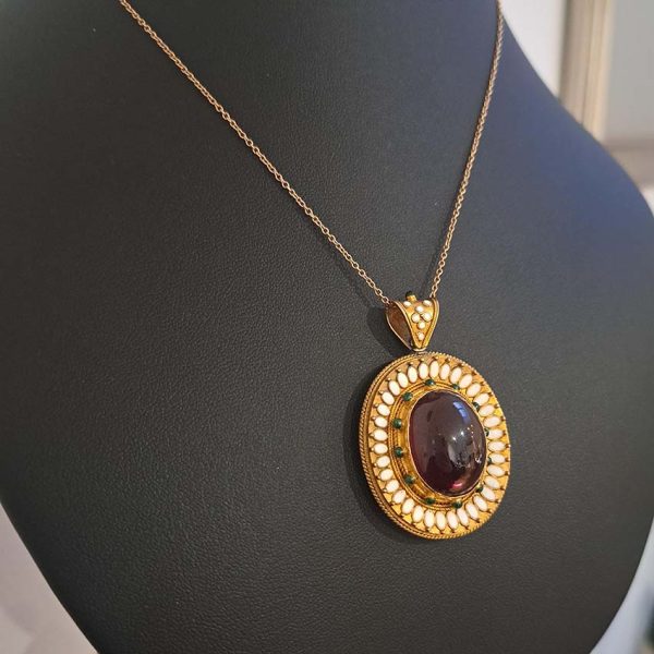 Antique Archaeological Revival Garnet Enamel and Gold Pendant, yellow gold pendant with large oval cabochon-cut garnet accented with white enamel and green enamel decorated surround