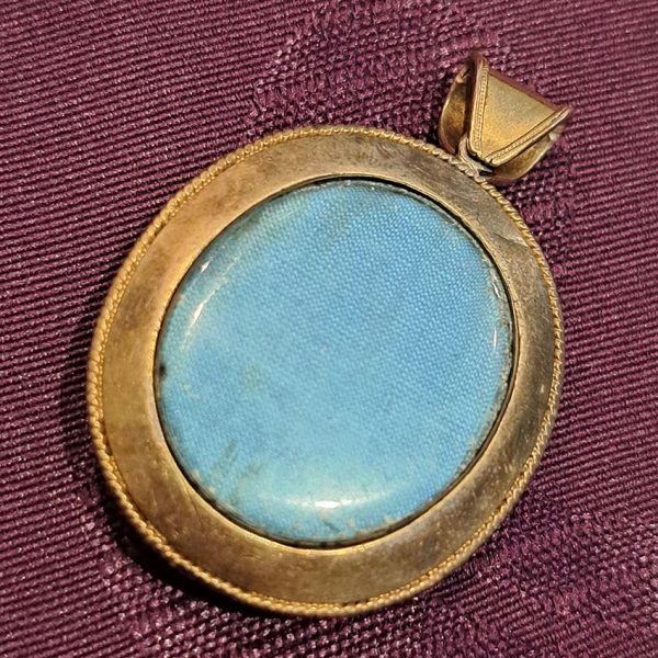 Antique Archaeological Revival Garnet Enamel and Gold Pendant, yellow gold pendant with large oval cabochon-cut garnet accented with white enamel and green enamel decorated surround