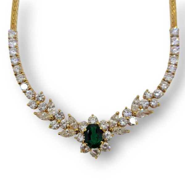 Oval Emerald and Diamond Floral Cluster Pendant Necklace, emerald and diamond flower cluster flanked by diamonds in delicate leaf design to line of brilliant-cut diamonds in 18ct yellow gold