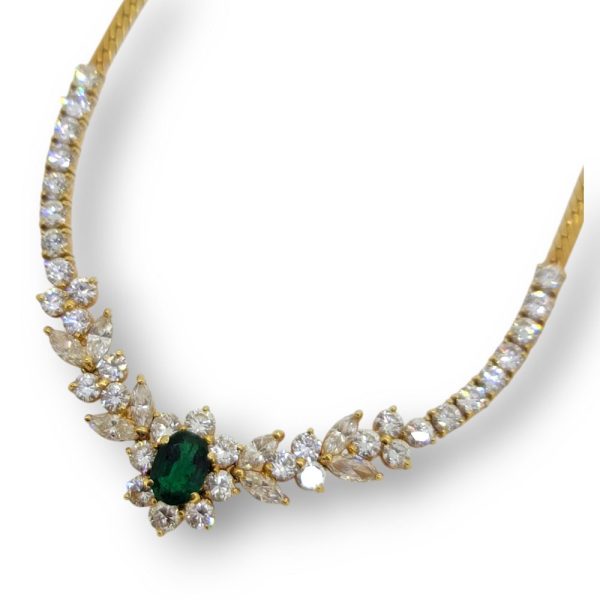 Oval Emerald and Diamond Floral Cluster Pendant Necklace, emerald and diamond flower cluster flanked by diamonds in delicate leaf design to line of brilliant-cut diamonds in 18ct yellow gold
