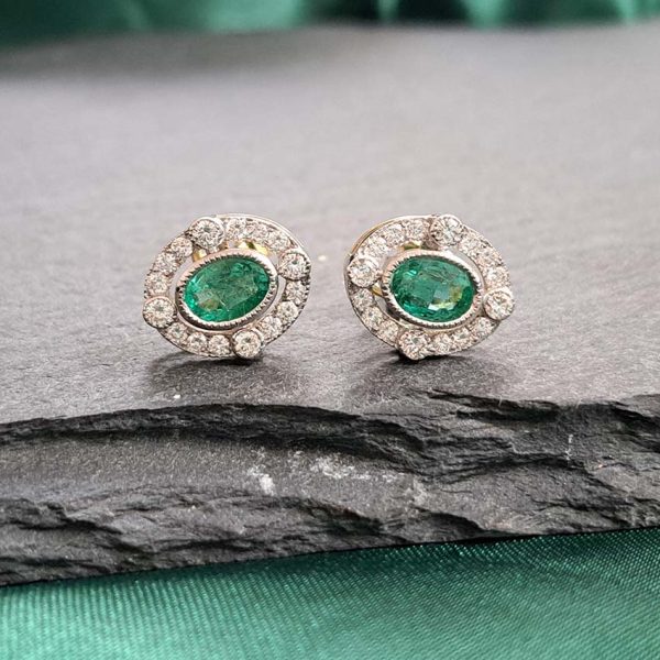 Contemporary Emerald and Diamond Oval Cluster Stud Earrings, 1.55ct emeralds with fixed border of diamonds with four focal at compass points in 18ct gold