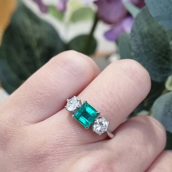 Art Deco Colombian Emerald and Diamond Trilogy Three Stone Engagement Ring, 1.25ct octagonal step-cut Colombian emerald flanked by 1ct old European transition cut diamonds in platinum