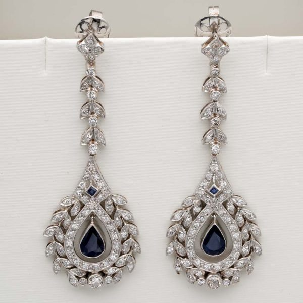 Edwardian Belle Epoque Antique Sapphire and Diamond Cluster Drop Earrings in Platinum, pear-shaped blue sapphires suspended within diamond wreath clusters from diamond leaf work drops, Circa 1905