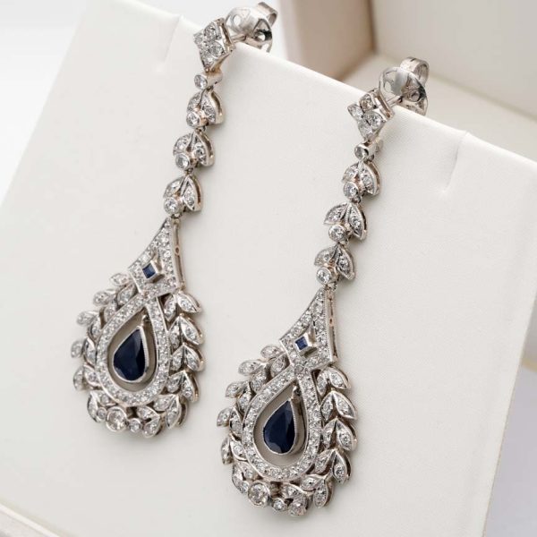 Antique Belle Epoque Edwardian Sapphire and Diamond Cluster Drop Earrings in Platinum, pear-shaped blue sapphires suspended within diamond wreath clusters from diamond leaf work drops, Circa 1905