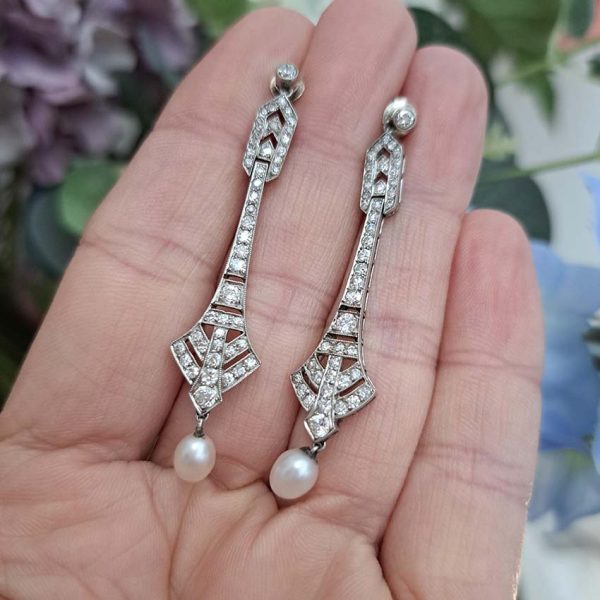 Antique Art Deco Natural Pearl and Diamond Drop Earrings, graduated geometric designs studded with 2 carats of sparkling diamonds leading to natural pearl pendant drops in platinum
