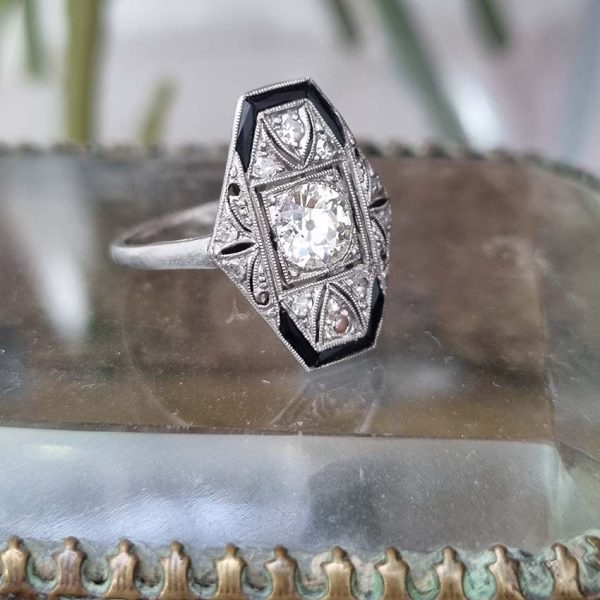 Art Deco Old Cut Diamond and Onyx Cluster Plaque Ring, 0.70ct old mine-cut diamond within tapered geometric surround of sparkling diamonds accented with rich black onyx in platinum. Circa 1920s