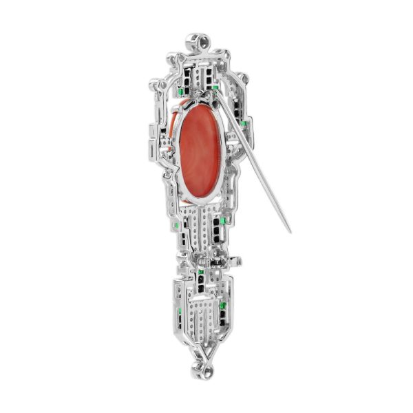 Art Deco Inspired Coral Onyx and Diamond Brooch, vivid orange 6.32ct oval coral within diamond geometric frame with contrasting black onyx and green emerald accents in 14ct white gold