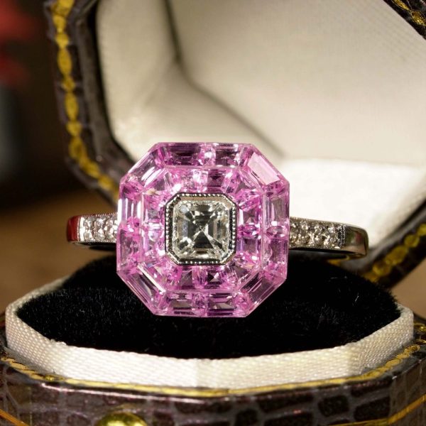 Asscher Cut Diamond and Pink Sapphire Engagement Ring, 0.30ct Asscher-cut diamond is surrounded by invisible set vibrant pink sapphires creating solid solitaire design in 18ct white gold with diamond-set shoulders