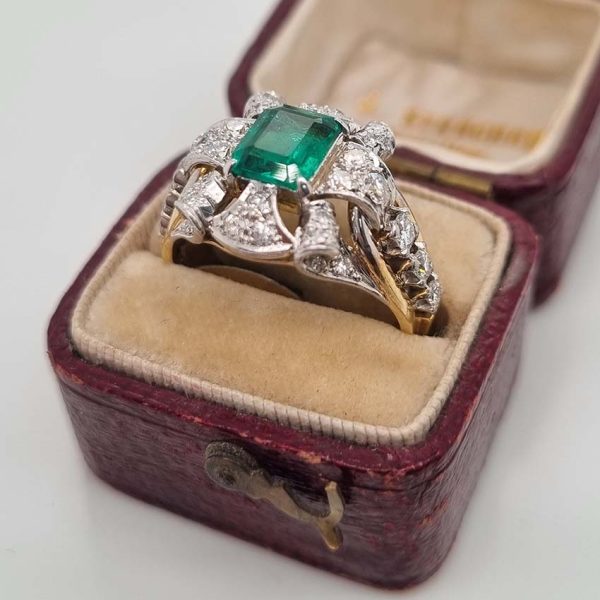 Vintage Colombian Emerald and Diamond Cluster Dress Ring, 0.81ct emerald-cut Colombian emerald within decorative fan design diamond surround to arched shoulders with central diamonds in 18ct yellow gold. Circa 1950s