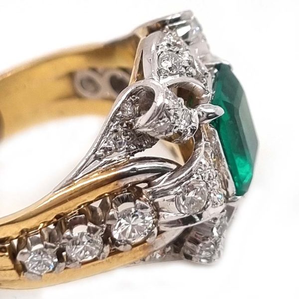 Vintage Colombian Emerald and Diamond Cluster Dress Ring, 0.81ct emerald-cut Colombian emerald within decorative fan design diamond surround to arched shoulders with central diamonds in 18ct yellow gold. Circa 1950s