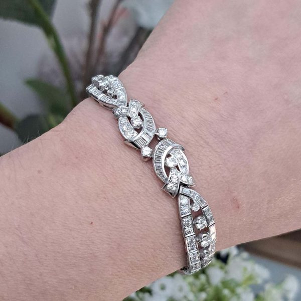 Late Art Deco Diamond Bracelet in Platinum, composed of a mirrored symmetrical buckle and swirl design set with sparkling diamonds