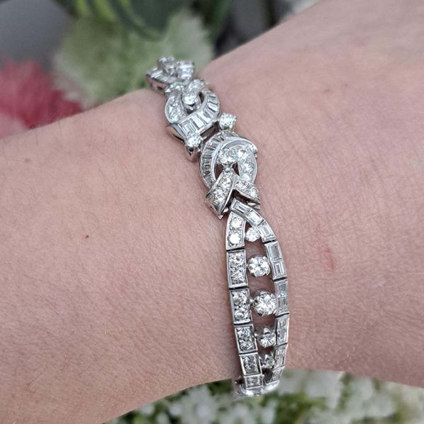Late Art Deco Diamond Bracelet in Platinum, composed of a mirrored symmetrical buckle and swirl design set with sparkling diamonds