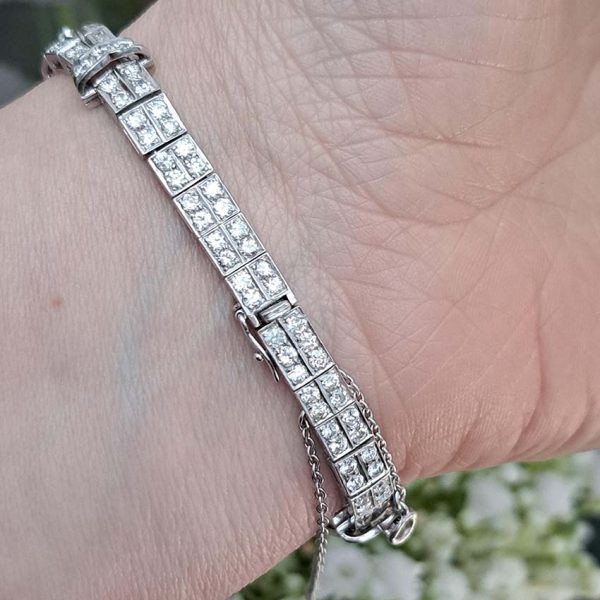 Late Art Deco Diamond Bracelet in Platinum, composed of a mirrored symmetrical buckle and swirl design set with sparkling diamonds