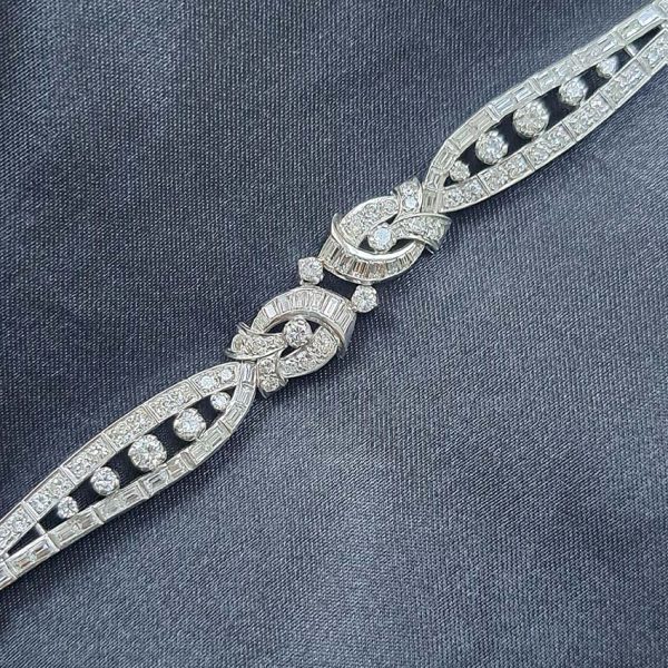 Late Art Deco Diamond Bracelet in Platinum, composed of a mirrored symmetrical buckle and swirl design set with sparkling diamonds