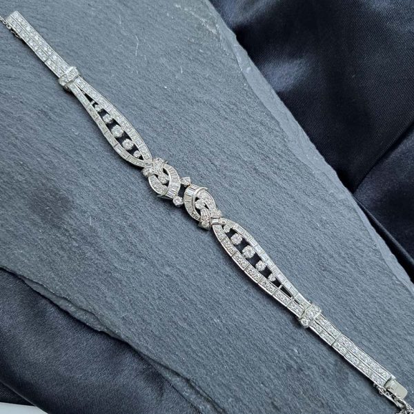 Late Art Deco Diamond Bracelet in Platinum, composed of a mirrored symmetrical buckle and swirl design set with sparkling diamonds