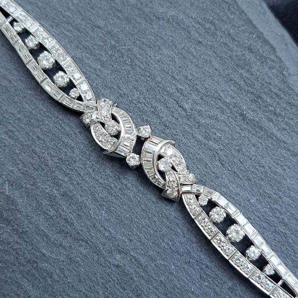 Late Art Deco Diamond Bracelet in Platinum, composed of a mirrored symmetrical buckle and swirl design set with sparkling diamonds