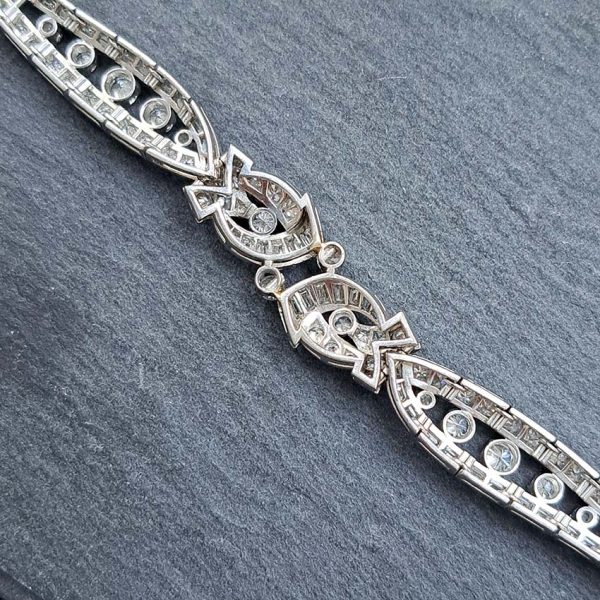 Late Art Deco Diamond Bracelet in Platinum, composed of a mirrored symmetrical buckle and swirl design set with sparkling diamonds