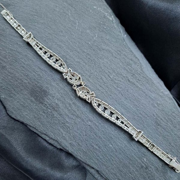 Late Art Deco Diamond Bracelet in Platinum, composed of a mirrored symmetrical buckle and swirl design set with sparkling diamonds