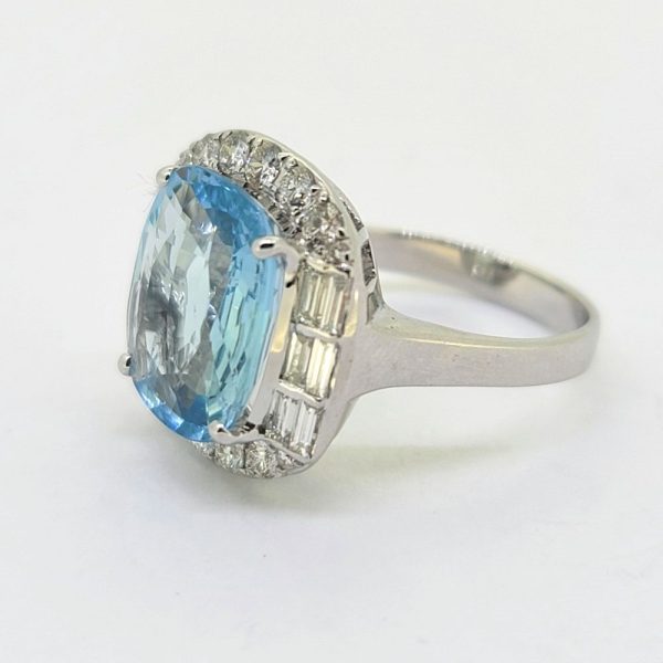 Contemporary 4.64ct Cushion Cut Aquamarine and Diamond Cluster Ring, 4.64ct cushion-shaped aquamarine surrounded by diamonds, with brilliant-cut diamonds to the top and bottom accented with baguette-cut diamonds to the sides in 18ct white gold