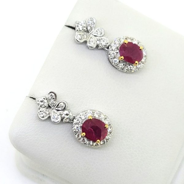 1.20ct Oval Ruby and Diamond Cluster Drop Earrings, oval red rubies surrounded by halos of round brilliant-cut diamonds suspended from butterfly shaped tops set with sparkling diamonds in 14ct white gold