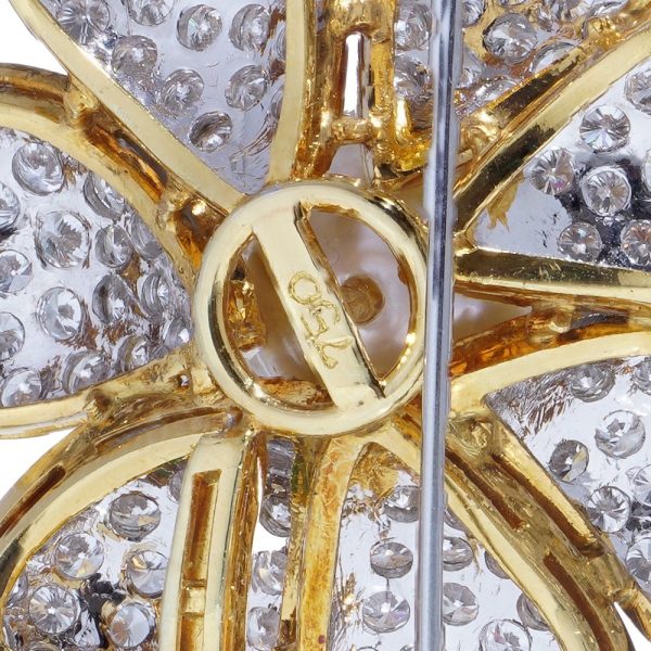 Floral brooch with pearl, diamonds and emeralds in gold.