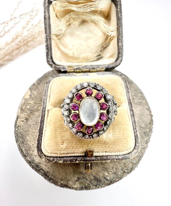 Early Victorian Antique Moonstone Ruby and Diamond Cluster Ring, oval cabochon moonstone surrounded by ruby petals within outer halo border of old-cut diamonds in silver to 18ct yellow gold. Mid 19th century Circa 1865
