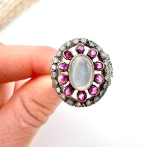 Early Victorian Antique Moonstone Ruby and Diamond Cluster Ring, oval cabochon moonstone surrounded by ruby petals within outer halo border of old-cut diamonds in silver to 18ct yellow gold. Mid 19th century Circa 1865