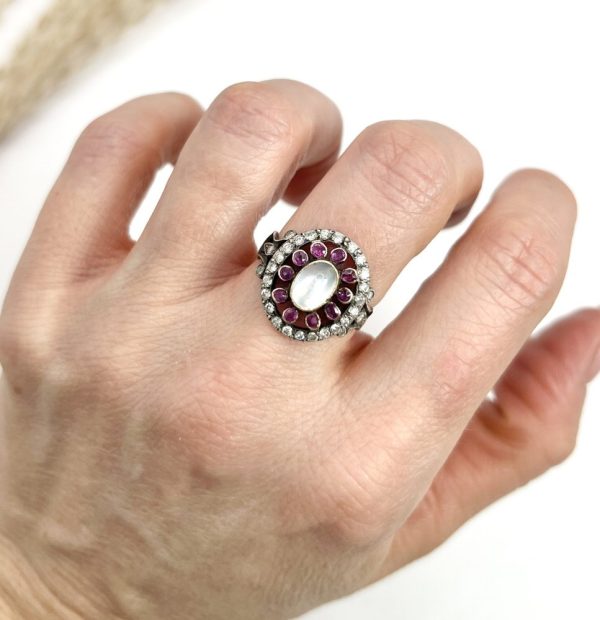 Early Victorian Antique Moonstone Ruby and Diamond Cluster Ring, oval cabochon moonstone surrounded by ruby petals within outer halo border of old-cut diamonds in silver to 18ct yellow gold. Mid 19th century Circa 1865