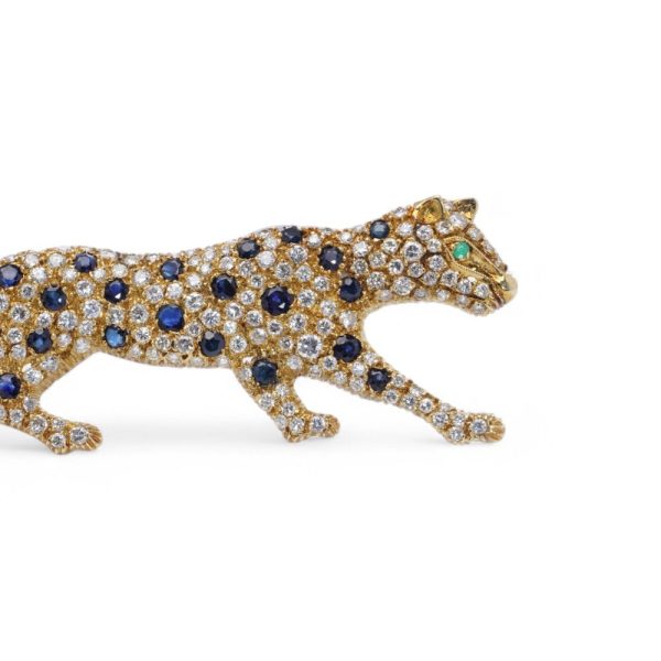 Gold panther brooch with diamonds, sapphires and an emerald.
