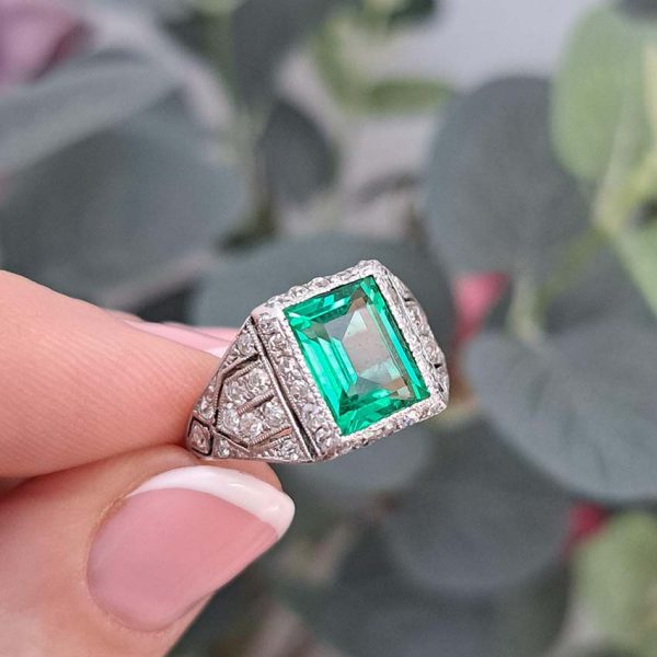 Belle Epoque Edwardian Antique 2.10ct Emerald and Diamond Cluster Ring in Platinum, 2.10ct rectangular step-cut vivid green emerald in diamond mount with openwork design to shoulders and scrolling gallery with engraved shank. Circa 1900