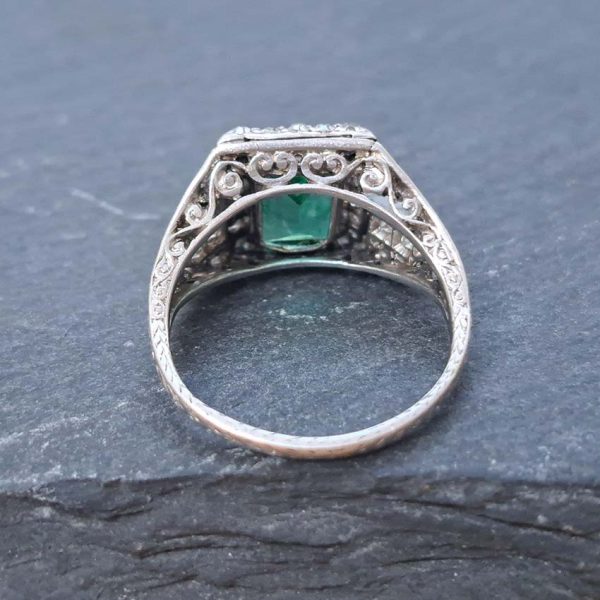 Belle Epoque Edwardian Antique 2.10ct Emerald and Diamond Cluster Ring in Platinum, 2.10ct rectangular step-cut vivid green emerald in diamond mount with openwork design to shoulders and scrolling gallery with engraved shank. Circa 1900