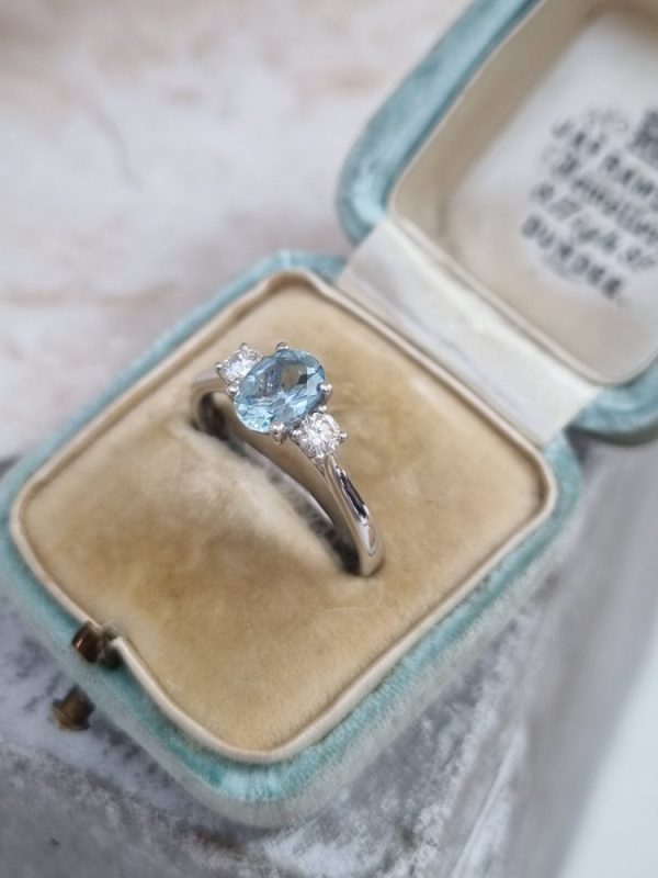 Three stone engagement ring with a 0.61ct oval cut aquamarine and 0.20ct of round cut diamonds, set in 18ct white gold