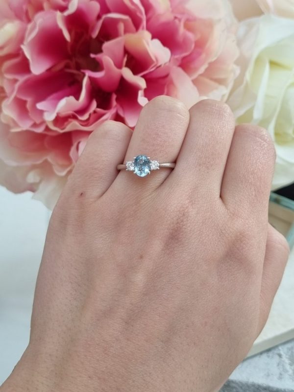 Three stone engagement ring with a 0.61ct oval cut aquamarine and 0.20ct of round cut diamonds, set in 18ct white gold