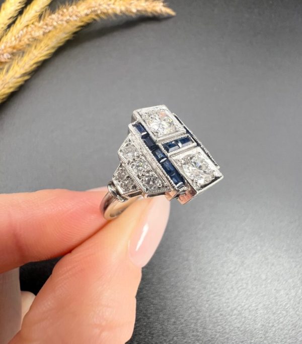 Art Deco Style Sapphire and Diamond Geometric Plaque Ring, two round brilliant cut diamonds in square bezel settings bordered by calibre sapphires in 18ct white gold with diamond stepped shoulders