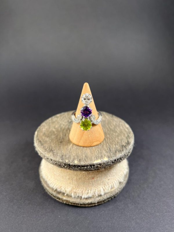 Edwardian Antique French Suffragette Amethyst Peridot Diamond Three Stone Ring, graduating trilogy of peridot amethyst and diamond arranged vertically up the finger when worn in 18ct white gold on diamond-set band with French eagles head stamp