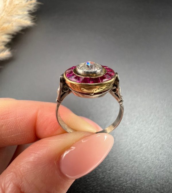 Antique Art Deco Diamond and Ruby Halo Target Cluster Engagement Ring, 0.65ct diamond framed by border of calibre red rubies in platinum and 18ct yellow gold. Circa 1920s