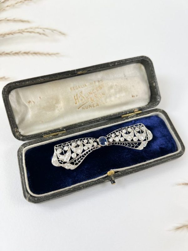 Vintage Antique Art Deco 3.4ct Old Cut Diamond and Sapphire Bow Brooch in Platinum, 1ct old cushion cut sapphire in diamond encrusted platinum decorative pierced framework with original antique velvet-lined fitted box. Circa 1920s